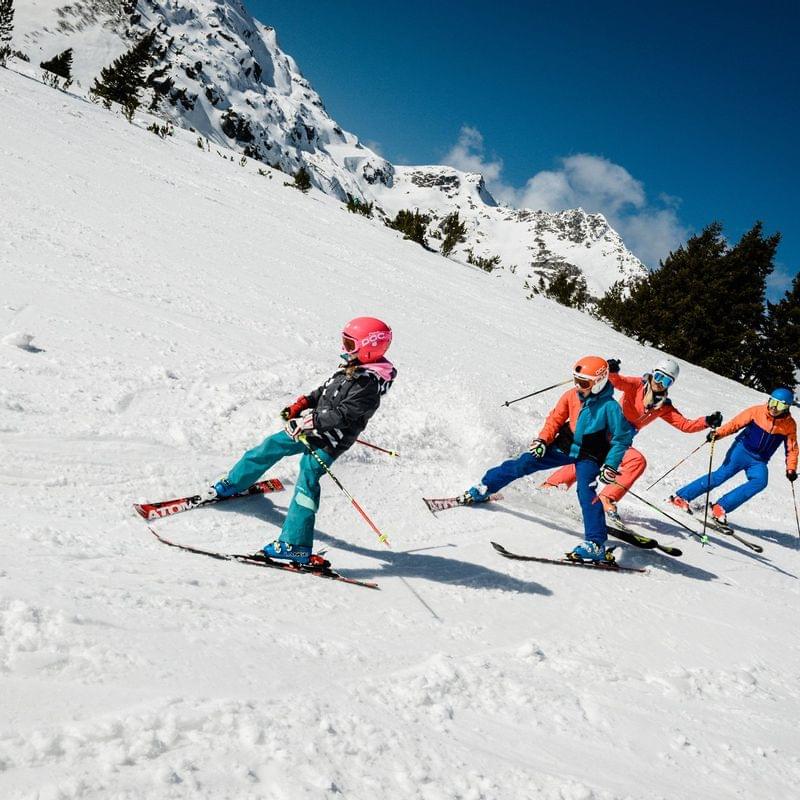 Gruppe fährt bei Sonnenschein die verschneite Berghang hinunter